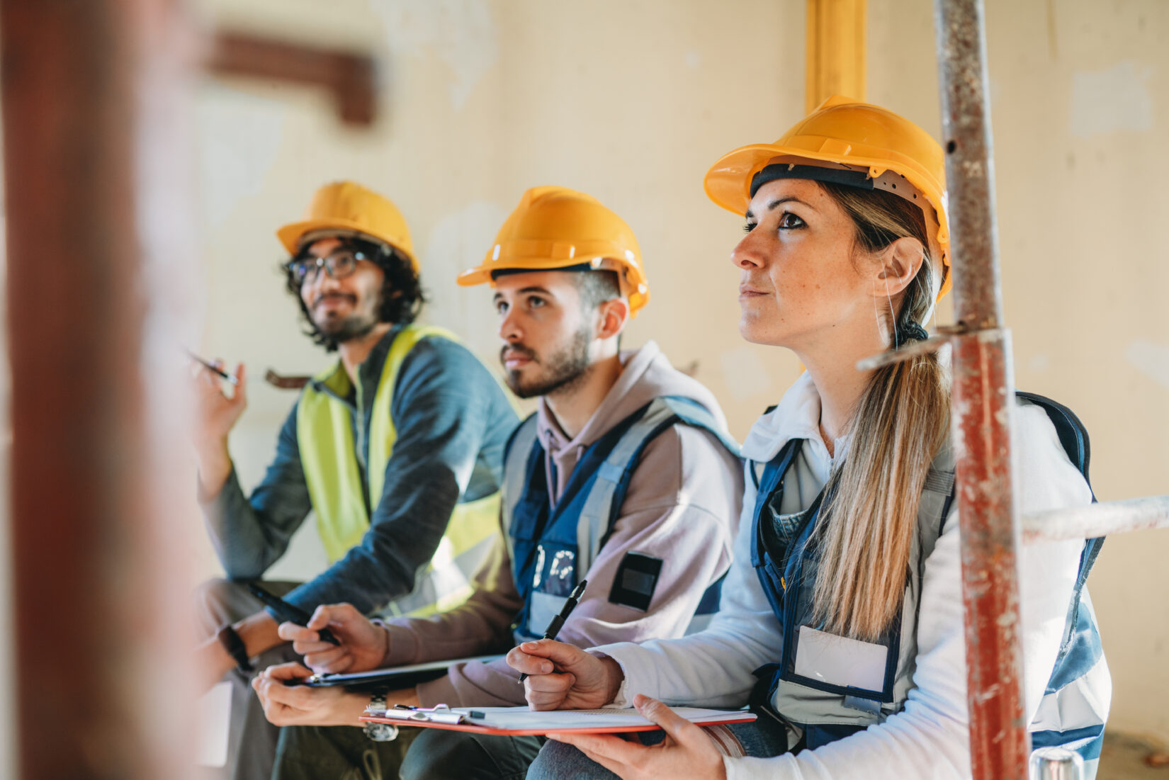 Three people are listening to their foreman on a construction site